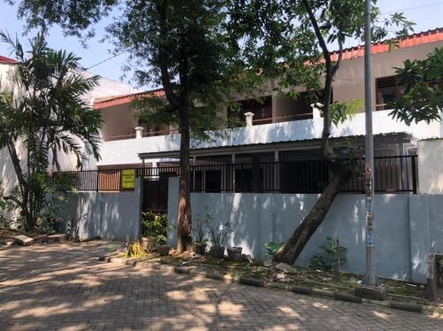 a building with a fence and trees in front of it at Hotel O Rumah Oma Syariah in Kupang