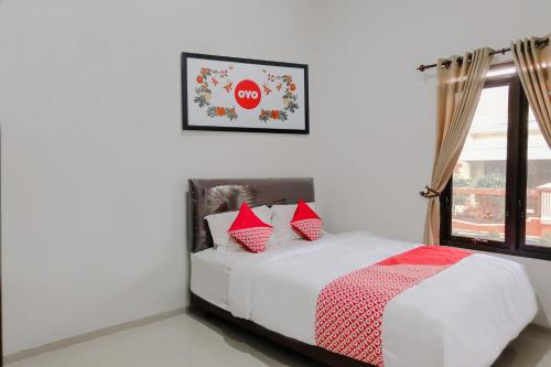 a bedroom with a bed with red pillows and a window at Hotel O Embun Pagi Syariah Residence in Malang