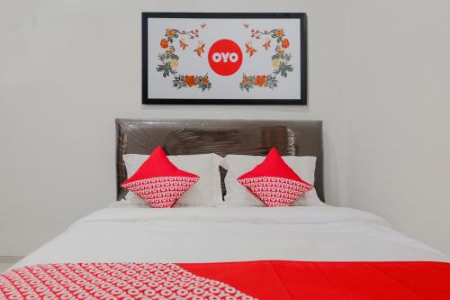 a bed with red and white pillows and a no sign at Hotel O Embun Pagi Syariah Residence in Malang