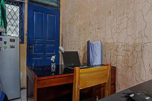 a desk with a laptop on it with a blue door at OYO Life 92684 Kost Mutiara Nirwana in Gandang