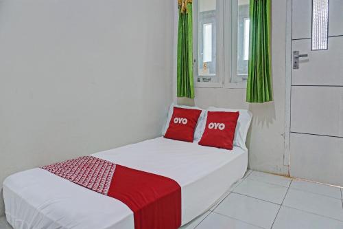 un letto bianco con cuscini rossi in una stanza di OYO Life 92684 Kost Mutiara Nirwana a Gandang
