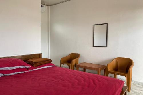 a bedroom with a bed and two chairs and a mirror at OYO Life 90960 Putih Salju Homestay Syariah in Parit