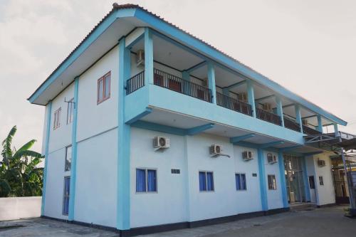 a blue and white building with a balcony at Hotel O Homiko in Pacitan