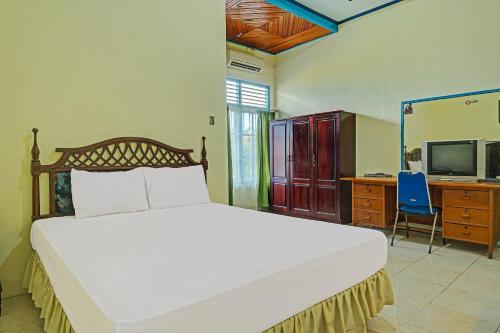 a bedroom with a bed and a desk and a television at Capital O 91806 Hotel Batu Suli in Palangkaraya