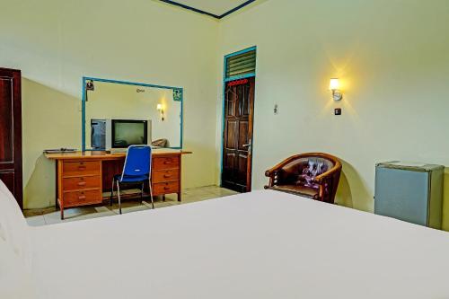a bedroom with a bed and a desk and a mirror at Capital O 91806 Hotel Batu Suli in Palangkaraya