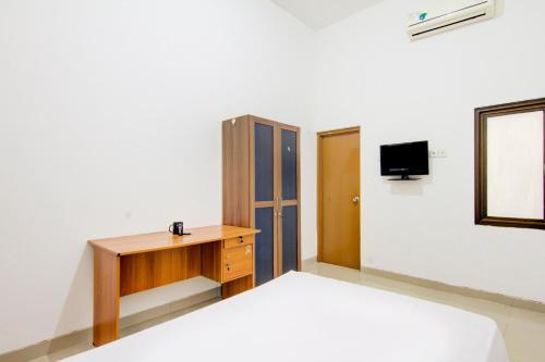 a bedroom with a bed and a desk and a tv at OYO Life 89990 Kost Waterfront 75 Sub in Surabaya