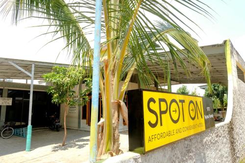 a yellow sign on the side of a building with a palm tree at Hotel O Ilyasa Family in Madiun