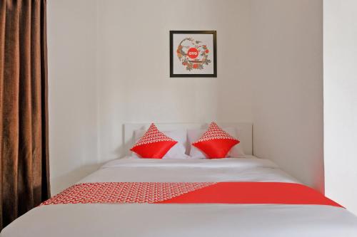 a bedroom with a bed with red pillows at Hotel O Kina Family Residence Syariah in Malang