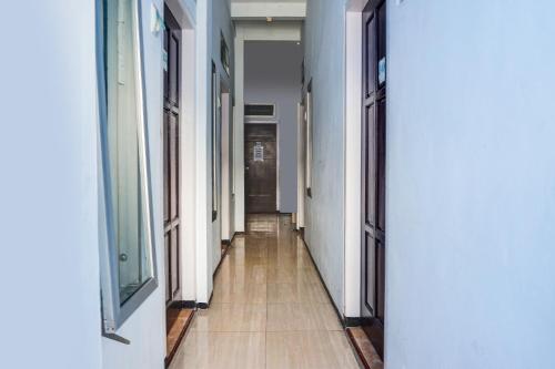 a hallway with white walls and a wooden floor at OYO 91926 Serayu Sumbersari Homestay in Jenggrik