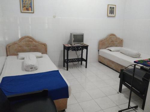 a bedroom with two beds and a tv on a table at EXPRESS O 91176 Hotel Puri Gandaria in Parepare