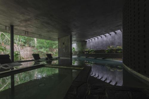 een zwembad in een gebouw met stoelen bij Charming Tulum Getaway in Prime Location in Tulum