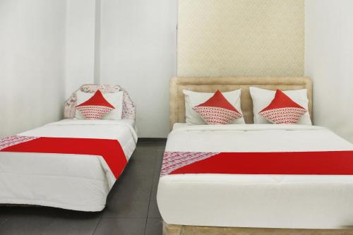 two beds in a room with red and white sheets at Hotel O Wisma Hulubalang in Palembang
