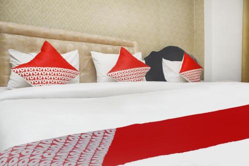 a bed with red and white pillows on it at Hotel O Wisma Hulubalang in Palembang