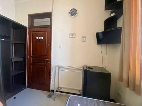 a room with a tv and a clock on the wall at OYO Life 93202 Pentagon Homestay Syariah in Surabaya