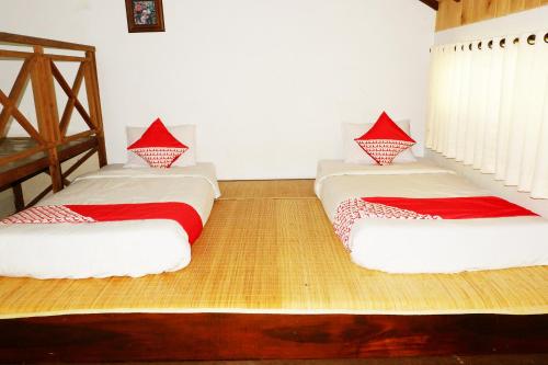 two beds in a room with red and white sheets at Hotel O Cemara's Homestay in Batu