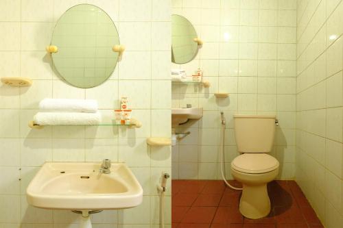 a bathroom with a toilet and a sink and mirrors at Hotel O Cemara's Homestay in Batu