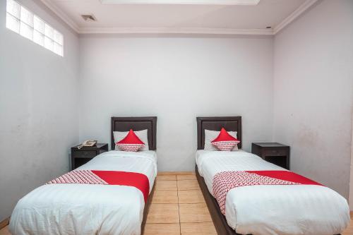 two beds in a room with red pillows on them at Hotel O Bunga Karang Hotel in Bekasi