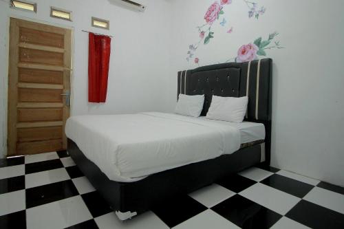 a bed in a room with a black and white checkered floor at Hotel O Wisma Ria in Lubuklinggau