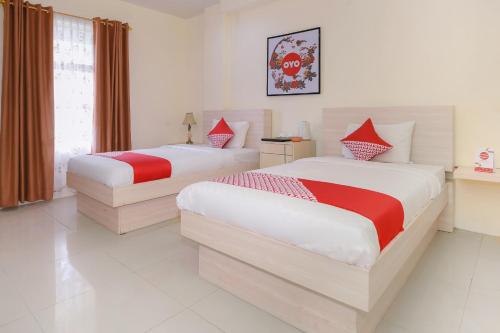 a bedroom with two beds with red and white sheets at Capital O 854 Ub Caisar Hotel in Banda Aceh