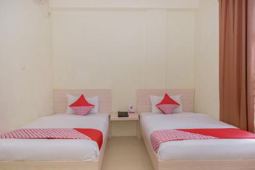 two beds with red pillows in a room at Capital O 854 Ub Caisar Hotel in Banda Aceh