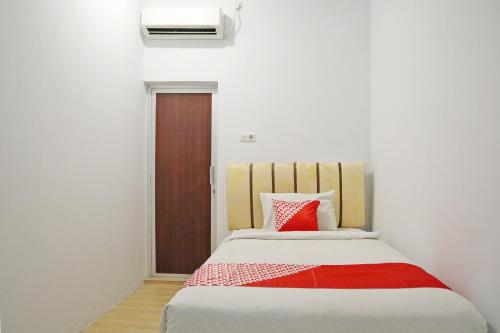 a bedroom with a bed with a red and white blanket at Hotel O M Authentic Kost Man in Padang