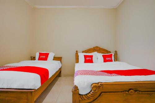 two beds in a room with red and white sheets at Hotel O Kenari House Syariah in Yogyakarta