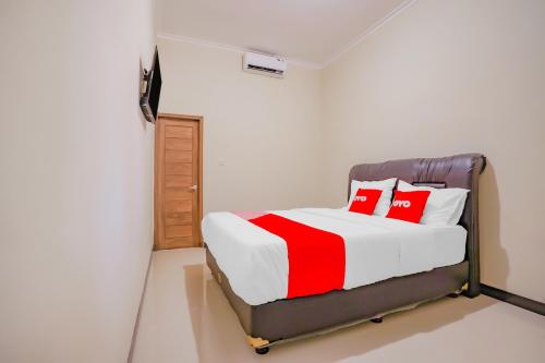 a bedroom with a bed with red and white pillows at Hotel O Kenari House Syariah in Yogyakarta