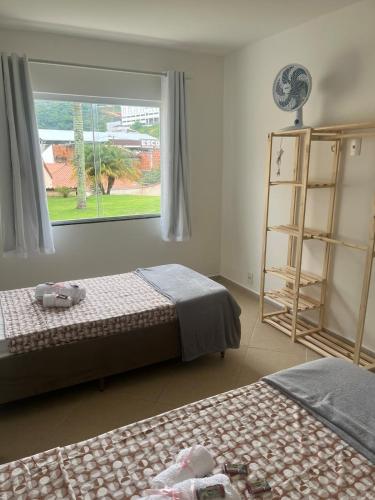 a bedroom with two beds and a window at Casa Dedeia Fest JF Marilândia in Juiz de Fora