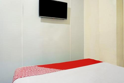a room with a bed with a flat screen tv on the wall at Hotel O J&b Room Pramuka in Jakarta
