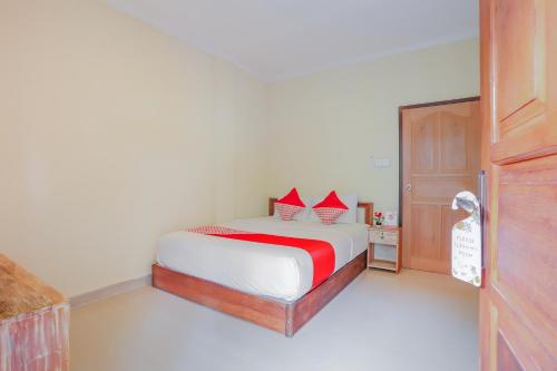 a bedroom with a bed with red pillows on it at OYO Life 90301 Hidden Village Uluwatu in Jimbaran
