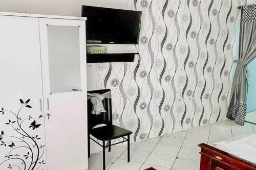a room with a chair and a tv on a wall at Hotel O Vida Homestay in Samarinda