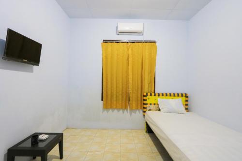 a room with a bed and a yellow curtain at OYO Life 2724 Wisma Wijaya in Banyuwangi