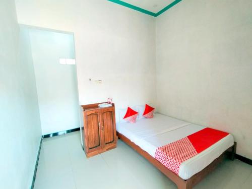 a small bedroom with a bed and a wooden cabinet at Hotel O Griya Annisa in Tegal