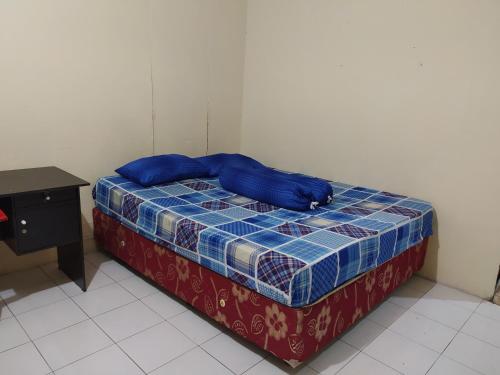 a bed with blue pillows on it in a room at Hotel O Batu Putih Homestay in Makassar