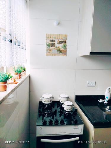 a kitchen with a stove with four pots on it at Apartamento à 3min do Aeroporto in São José dos Pinhais
