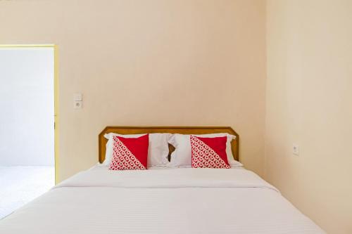 a bed with red and white pillows on it at Hotel O Lansano Residence Syariah in Padang