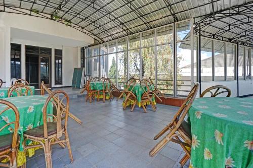 a dining room with tables and chairs and windows at Hotel O Victory in Batu