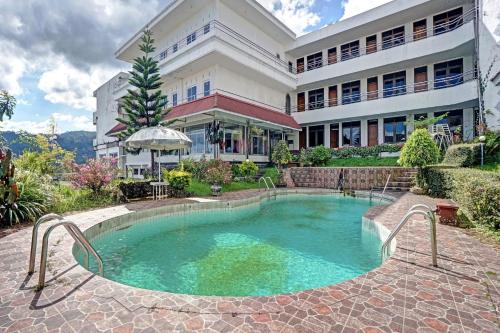 a swimming pool in front of a building at Hotel O Victory in Batu