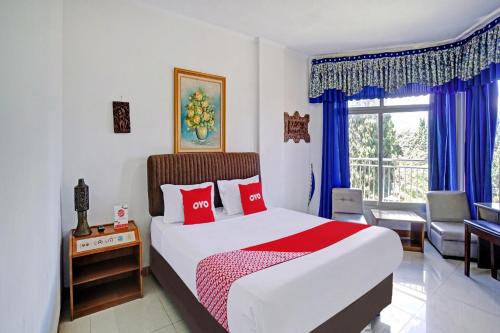 a bedroom with a bed with red pillows and a window at Hotel O Victory in Batu