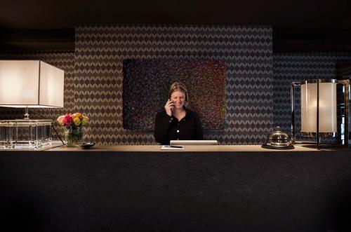 a woman sitting at a counter talking on a cell phone at Hotel Van Cleef in Bruges