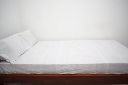 a bed with white sheets and pillows on it at OYO Life 93382 Gajayana Kost Female Only Syariah in Jenggrik
