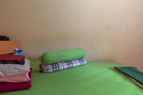 a room with a bed with green sheets and blankets at Hotel O Wisma Rima Melati in Tolo