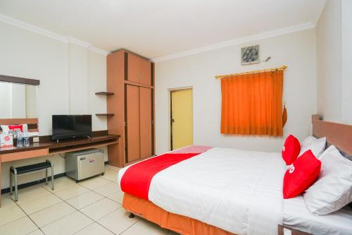 a bedroom with a bed and a desk and a television at Hotel O Graha Marina in Surabaya
