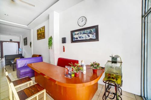 a living room with a table and a clock on the wall at Hotel O near Citraland formerly Brayan Guest House in Medan