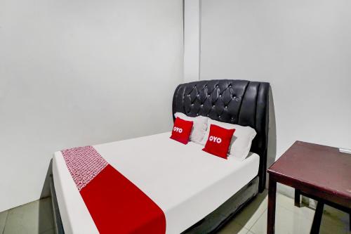 a bed with two red pillows on it next to a table at Hotel O near Citraland formerly Brayan Guest House in Medan