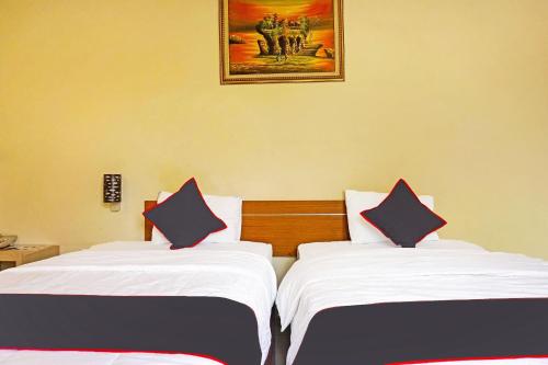 two beds in a room with a picture on the wall at Collection O 91409 Hotel Fiducia Otista 153 - 157 in Jakarta