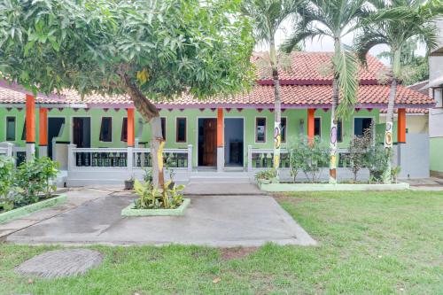 een huis met een palmboom ervoor bij Hotel O Griya Ketapang in Banyuwangi