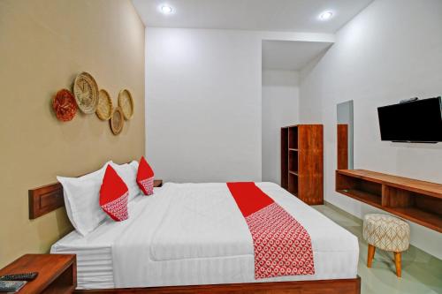 a bedroom with a bed with red pillows and a tv at Hotel O Madania Guesthouse Syariah in Mataram