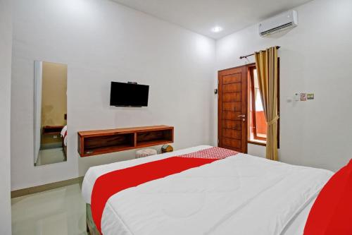 a bedroom with a bed and a tv on the wall at Hotel O Madania Guesthouse Syariah in Mataram