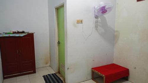 a room with a red stool and a fan on the wall at OYO Life 93712 Vanda Family in Blitar